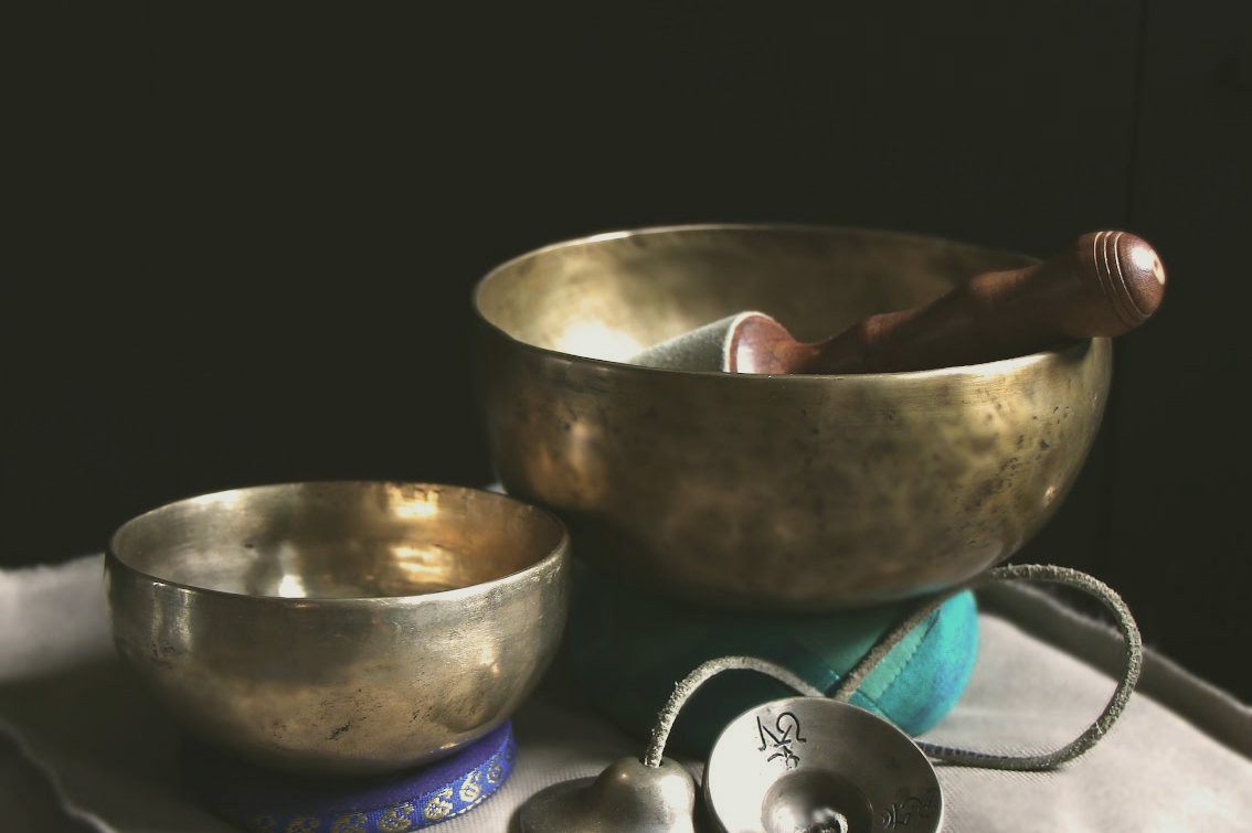 Twee klinkende metalen schalen en een stamper op een donkere achtergrond.